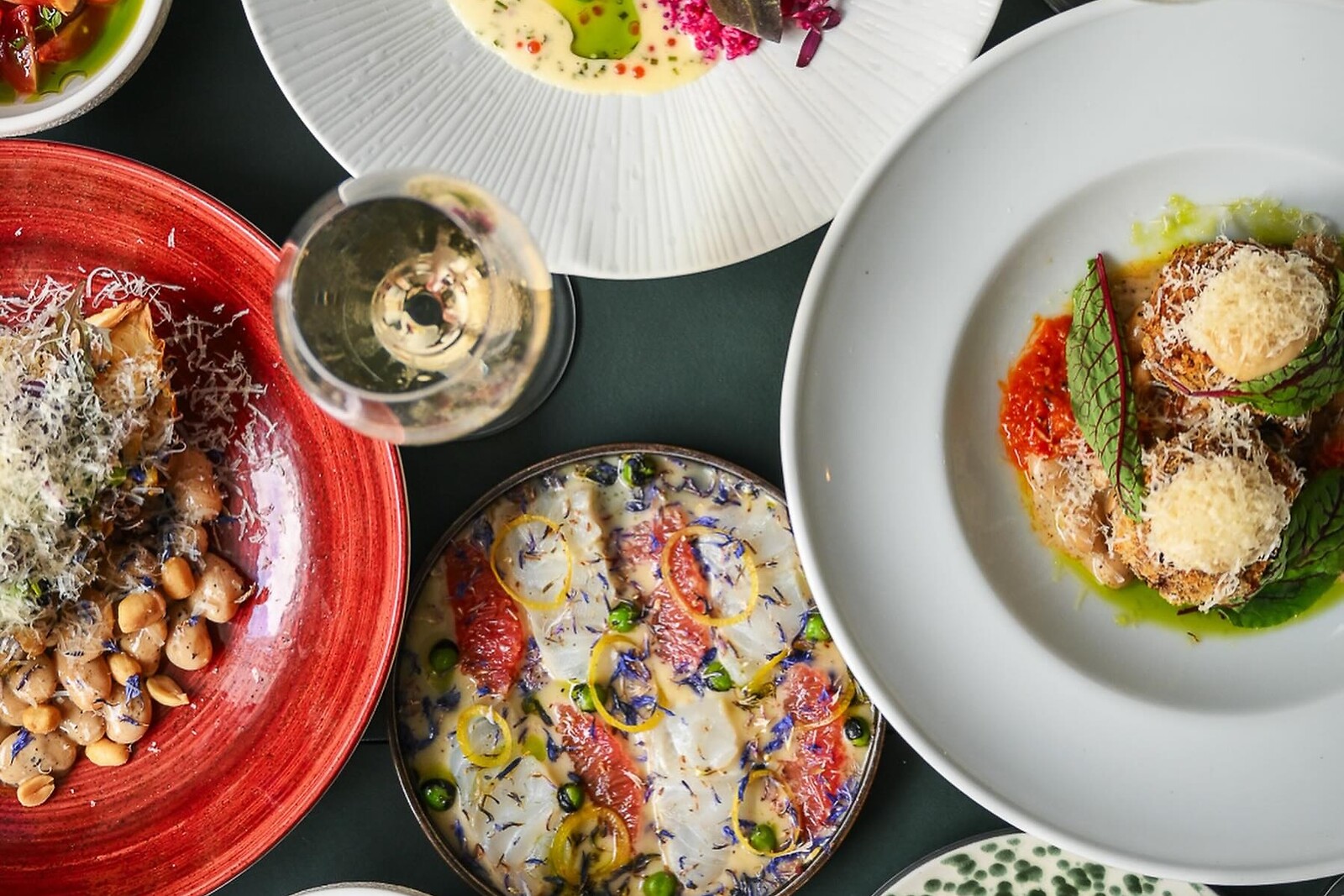 Fire anrettede gourmetretter på farvede tallerkener set oppefra